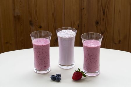 Three glasses of strawberry smoothie milkshake with strawberry on white tableの写真素材