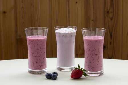 Three glasses of strawberry smoothie milkshake with strawberry on white tableの写真素材
