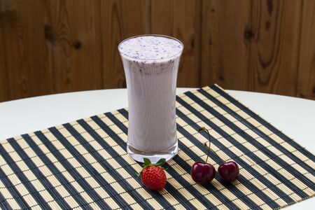One glass of strawberry smoothie milkshake with strawberry on striped rug white tableの写真素材