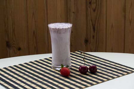 One glass of strawberry smoothie milkshake with strawberry on striped rug white tableの写真素材