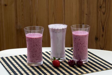 Three glasses of strawberry smoothie milkshake with strawberry on white tableの写真素材