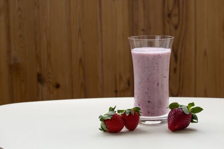 One glass of strawberry smoothie milkshake with strawberry on white tableの写真素材