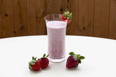 One glass of strawberry smoothie milkshake with strawberry on white tableの写真素材
