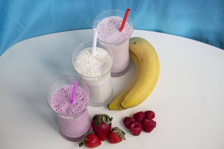 fresh fruit smoothie milkshake with berries and bananas blue backgroundの写真素材