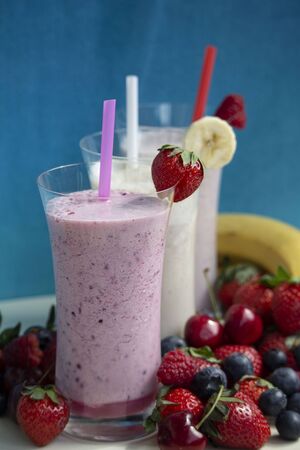 fresh fruit smoothie milkshake with berries and bananas blue backgroundの写真素材