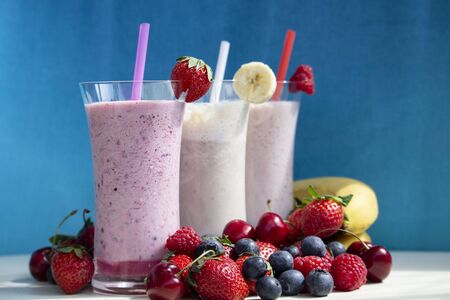 fresh fruit smoothie milkshake with berries and bananas blue backgroundの写真素材
