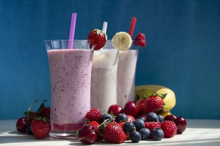 fresh fruit smoothie milkshake with berries and bananas blue backgroundの写真素材