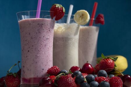 fresh fruit smoothie milkshake with berries and bananas blue backgroundの写真素材