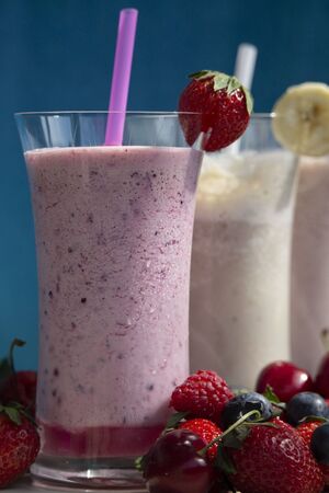 fresh fruit smoothie milkshake with berries and bananas blue backgroundの写真素材