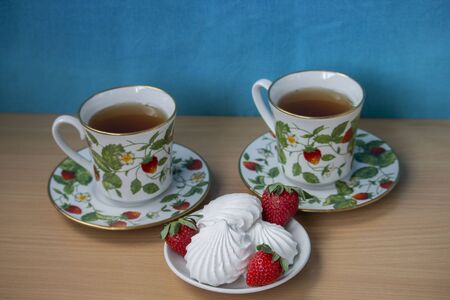 two cups of tea and marshmallow with strawberriesの写真素材