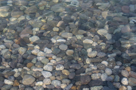 Gray black white brown pebbles stones under water blur backgroundの写真素材