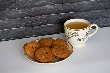 Cup of tea and cookies on a table in front of a brick wallの写真素材
