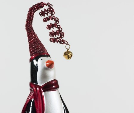 A figure of a black and white penguin wearing a red sparkling stocking cap adorned with a bell and a red scarfの写真素材