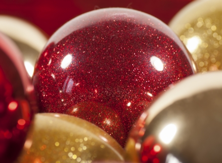 A red sparkling Christmas ball nestled among other gold and silver ballsの写真素材