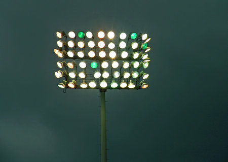 A photograph of a bank of stadium lights against a dark cloudy skyの写真素材