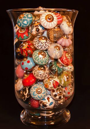 A glass container filled with painted drawer pulls in various colors and designs.の写真素材