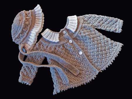 Photo of a hand-knitted grey sweater trimmed in white with a matching bonnet for a baby girlの写真素材