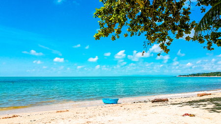 Sand Sea Sky at Samui island, Thailand with a small blue boat and the trees.の写真素材