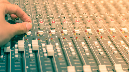 A sound engineer works with a music mixer with hand adjust the knobs.の写真素材