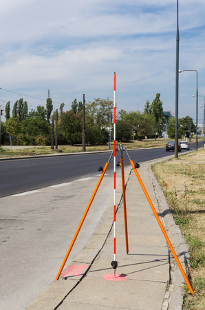 Offset rod mounted on a tripod placed near the road, pink tag on a pavementの写真素材