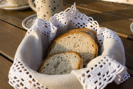 Slices of traditional bread on handmade napkin in basket on wooden table
