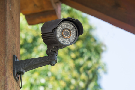 CCTV security camera mounted on garden wooden arbor or gateの写真素材