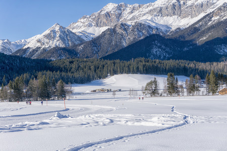 Winter mountains landscape with groomed ski track and blue sky in sunny dayの写真素材