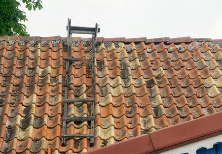 A wooden ladder on an old roof covered with ceramic tileの写真素材