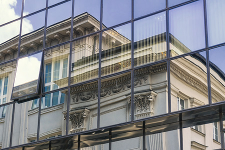 A reflection of an old historic building in the glass facade of a modern office building.の写真素材