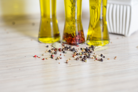 Colorful olive oil and spezialia, rosemary, pepper, oregano, allspice, bay leaf in the background. Selective focus.の写真素材