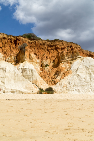 High cliffs along Falesia Beach and The Atlantic Ocean in Albufeira, Algarve, Portugal. Sunny summer day, blue sky with stormy clouds.の写真素材