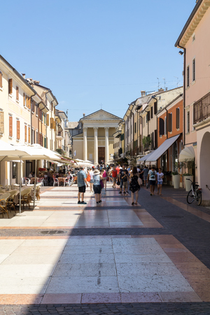 BARDOLINO, VENETO REGION, ITALY - AUGUST 7, 2017: People on main street of village of Bardolino in front of Parish Church.のeditorial素材