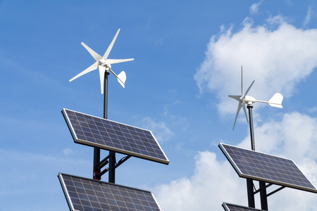 Small wind power generators and set of Solar panels agains blue sky with white clouds. Concept of renevable energy.の写真素材