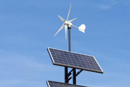 Small wind power generator and set of Solar panels agains blue sky. Concept of renevable energy.の写真素材