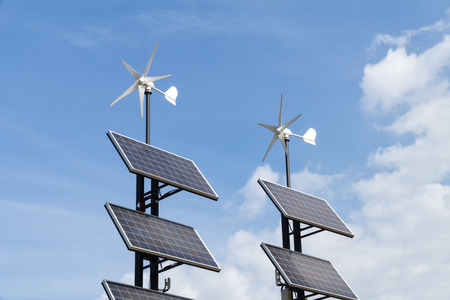 Small wind power generators and set of Solar panels agains blue sky with white clouds. Concept of renevable energy.の写真素材