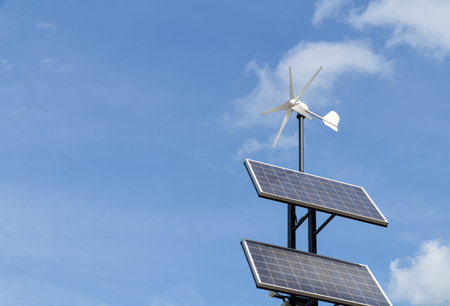 Small wind power generator and set of Solar panels agains blue sky with white clouds. Concept of renevable energy.の写真素材