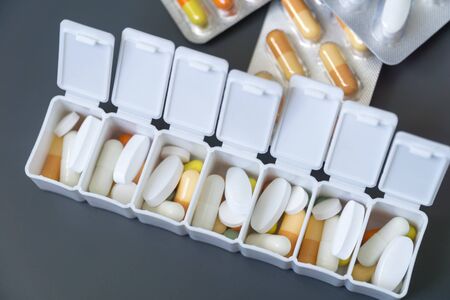 Medicine pills, tablets and capsules different colors in pill box on grey background, selective focus. Health care.の写真素材