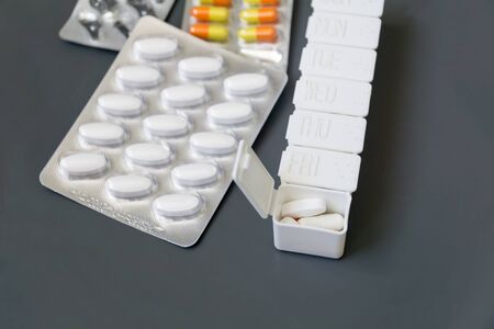 Medicine pills, tablets and capsules different colors in pill box on grey background, selective focus. Health care.の写真素材