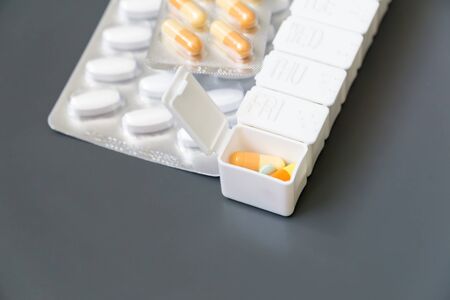 Medicine pills, tablets and capsules different colors in pill box on grey background, selective focus. Health care.の写真素材