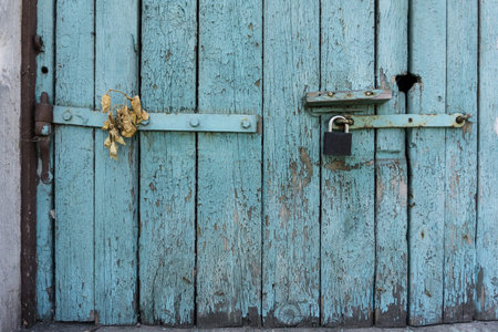 Old wooden door with blue painted planks closed with a padlock. Grunge background.の写真素材
