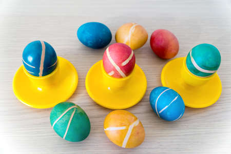 Colorful painted homemade easter eggs with modern pattern on yellow coasters on wooden table. Easter decoration, easter background.の写真素材