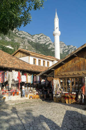 KRUJA, ALBANIA - SEPTEMBER 16, 2019: street market with souvenirs, craft items and small shops in Kruja (Kuje) Albania, Europe. Minaret, mountain and sky background.のeditorial素材