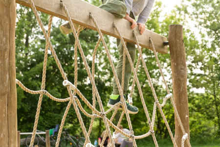 Active boy playing outdoors, kid climbing rope net at playground. Happy child enjoying activity in a...
