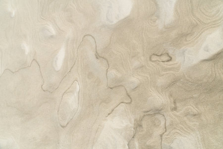 Wet beach sand texture. Natural, abstract beige background. Top view.
