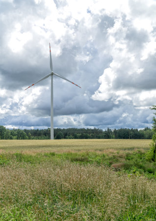 Rural landscape with wind turbine, windmill for electric power production - closeup, sky with stormy clouds in the background. Renewable energy, sustainability, environmental protection concept.の写真素材