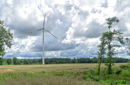 Rural landscape with wind turbine, windmill for electric power production - closeup, sky with stormy clouds in the background. Renewable energy, sustainability, environmental protection concept.の写真素材