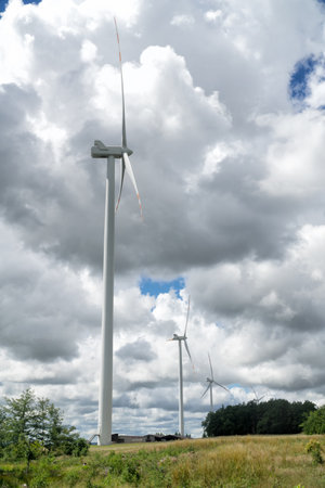Rural landscape with wind farm, windmills for electric power production, sky with stormy clouds in the background. Renewable energy, sustainability, environmental protection concept.の写真素材