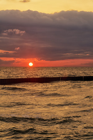 Seascape at sunset in stormy weather. Waves on the sea and dark clouds in the sky. Baltic Sea, Western Pomerania, Poland, Europe.の写真素材