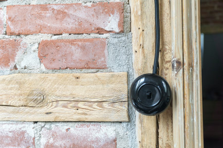 Vintage electrical switch, light button with black electric cable mounted on a half-timbered or timber-framed wall.の写真素材