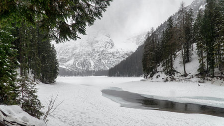 Frozen lake surface covered with snow. Foggy, rainy, winter landscape. Lake Braies, Lago di Braies in winter, Dolomites, Italy, Europe.の写真素材